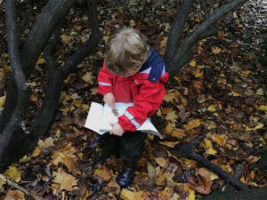 A child from Spring RAF Halton sitting outside with a book about wildlife.